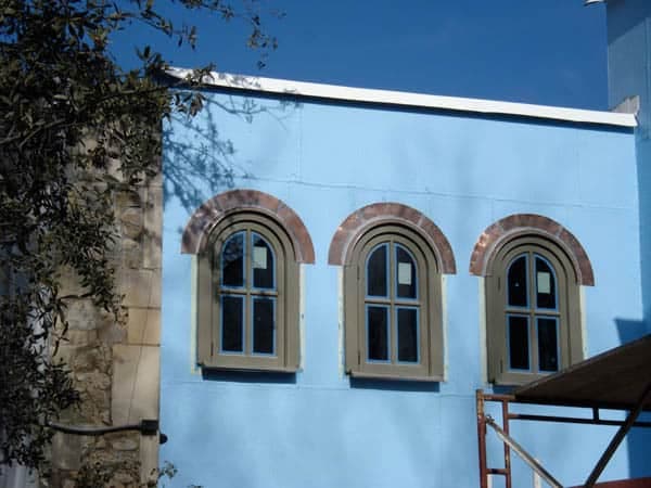 Copper arched window head flashing above three arched windows on a blue building