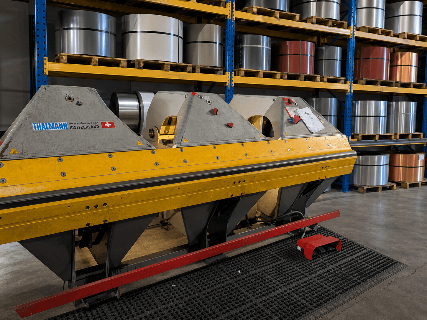 Close-up of the Thalmann folder at the AFS shop with coil stock on the racks behind